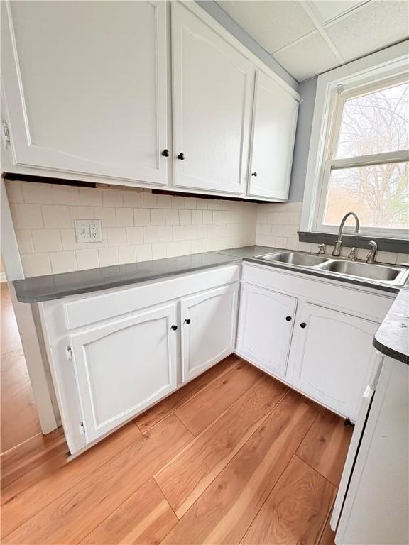 74 Pontiac St, Warwick, RI 02886 - kitchen featuring a sink, light wood-style flooring, white cabinets, and tasteful backsplash