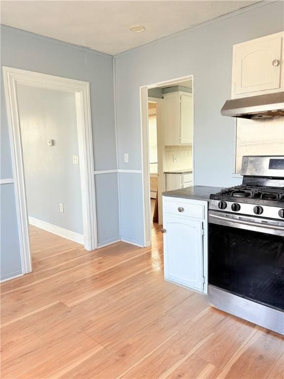 74 Pontiac St, Warwick, RI 02886 - kitchen with stainless steel gas stove, exhaust hood, white cabinets, light wood finished floors, and baseboards