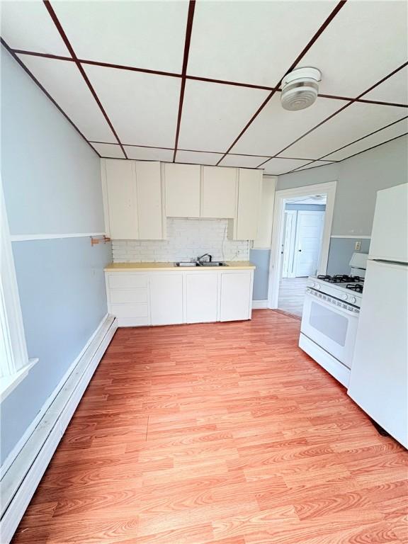 74 Pontiac St, Warwick, RI 02886 - kitchen featuring white appliances, baseboard heating, white cabinets, light countertops, and light wood-style flooring