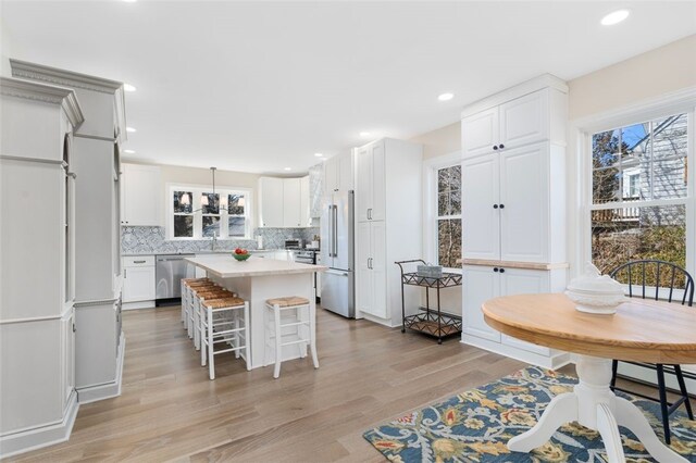 58 Austin St, South Kingstown, RI 02879 - kitchen with stainless steel appliances, light wood finished floors, a center island, light countertops, and tasteful backsplash
