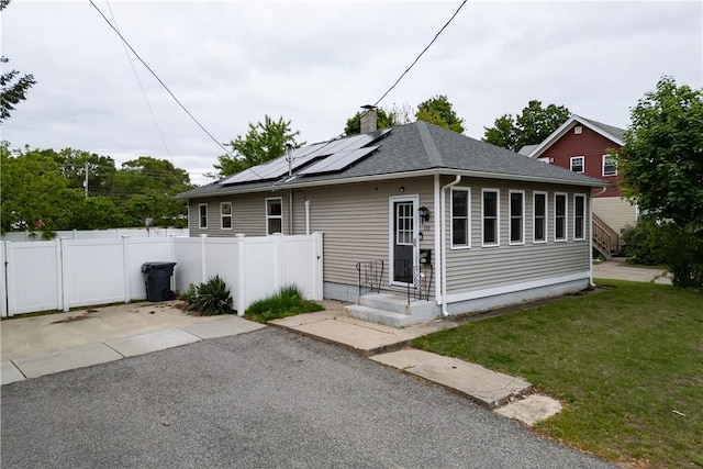 133 Broad St, Warwick, RI 02888 - view of front of property with roof mounted solar panels, a chimney, and a shingled roof