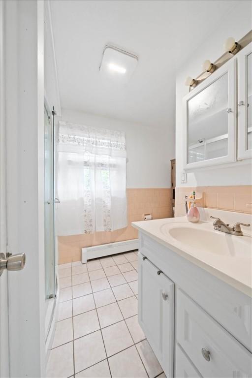 320 Beverage Hill Ave, Pawtucket, RI 02861 - bathroom featuring a baseboard radiator, vanity, a shower stall, tile patterned flooring, and wainscoting