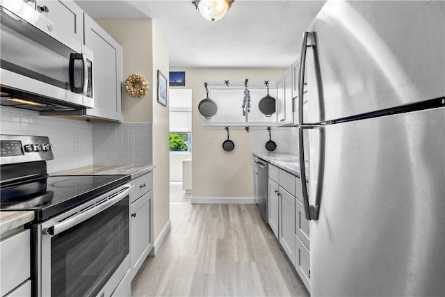 30 Brown St Unit 2, Narragansett, RI 02882 - kitchen with appliances with stainless steel finishes, decorative backsplash, light wood-style flooring, baseboards, and gray cabinetry