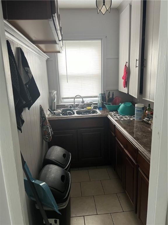 1097 Pontiac Ave, Cranston, RI 02910 - kitchen featuring a sink, light tile patterned floors, dark brown cabinets, and dark countertops