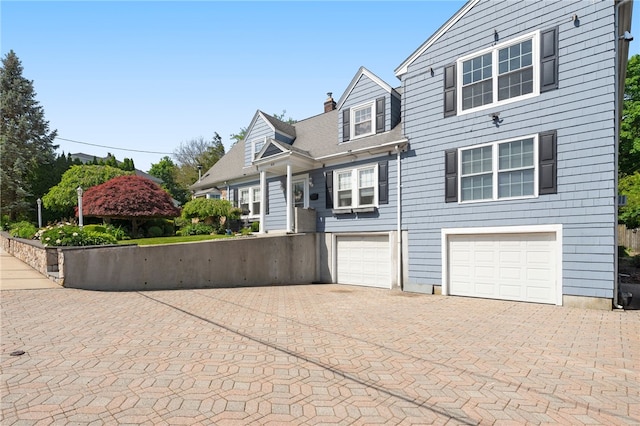 62 Andrews Ave, West Warwick, RI 02893 - view of front of home with decorative driveway, a garage, and a chimney