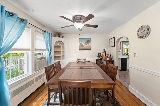 62 Andrews Ave, West Warwick, RI 02893 - dining space featuring radiator heating unit, wood-type flooring, a ceiling fan, arched walkways, and cooling unit