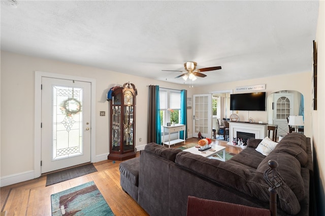 62 Andrews Ave, West Warwick, RI 02893 - living room featuring baseboards, ceiling fan, light wood-type flooring, a fireplace, and arched walkways