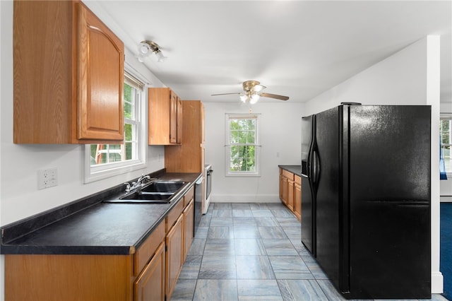 62 Andrews Ave, West Warwick, RI 02893 - kitchen with black fridge, a sink, dark countertops, ceiling fan, and brown cabinetry