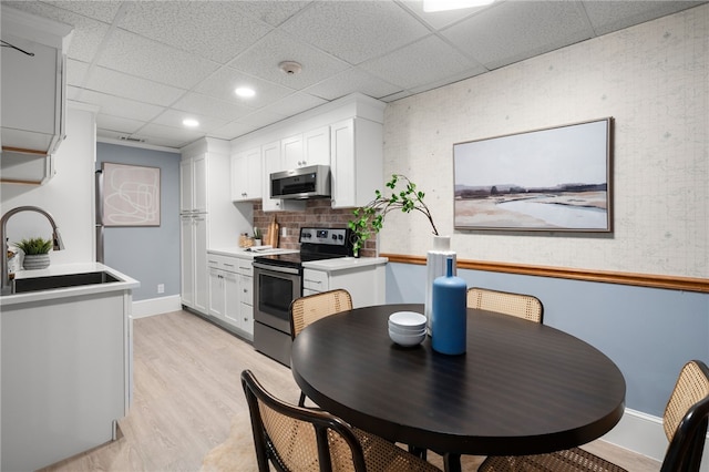 22 Halsey St Unit 1, Providence, RI 02906 - kitchen featuring stainless steel appliances, a drop ceiling, light wood finished floors, white cabinetry, and light countertops