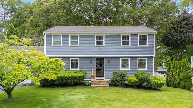 67 Hathaway Dr, West Warwick, RI 02893 - colonial-style house featuring a chimney, a front yard, and view of wooded area