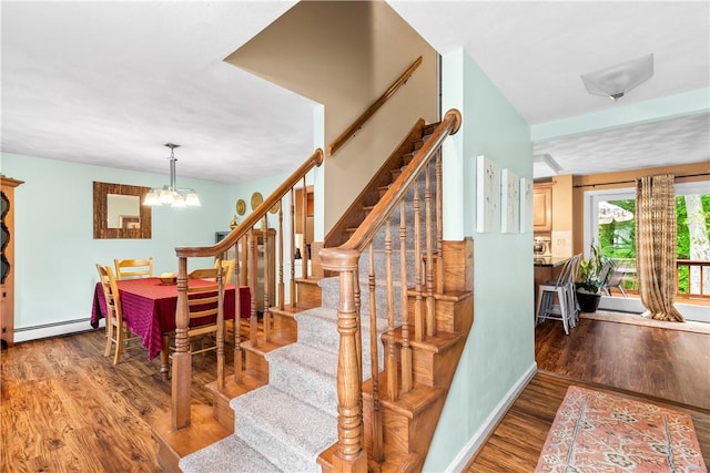 67 Hathaway Dr, West Warwick, RI 02893 - stairway with a baseboard radiator, wood finished floors, and a chandelier