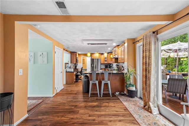 67 Hathaway Dr, West Warwick, RI 02893 - kitchen with stainless steel fridge, dark countertops, wood finished floors, a kitchen breakfast bar, and a peninsula