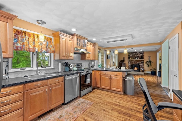 67 Hathaway Dr, West Warwick, RI 02893 - kitchen with stainless steel appliances, a sink, under cabinet range hood, light wood-style floors, and a peninsula