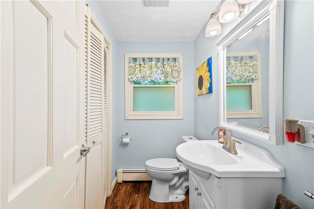 67 Hathaway Dr, West Warwick, RI 02893 - bathroom with a baseboard radiator, vanity, toilet, wood finished floors, and a closet