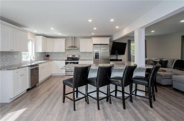 126 Hilton St, Tiverton, RI 02878 - kitchen featuring stainless steel appliances, wall chimney range hood, open floor plan, a sink, and a breakfast bar area