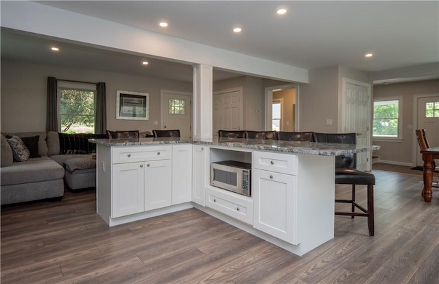 126 Hilton St, Tiverton, RI 02878 - kitchen featuring open floor plan, stainless steel microwave, a breakfast bar, white cabinets, and stone countertops