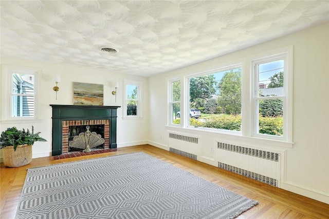 23 Robert Cir, Cranston, RI 02905 - unfurnished living room with radiator heating unit, wood finished floors, and a brick fireplace