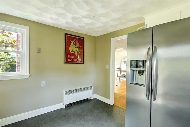 23 Robert Cir, Cranston, RI 02905 - kitchen with stainless steel refrigerator with ice dispenser, radiator, baseboards, arched walkways, and dark tile patterned floors