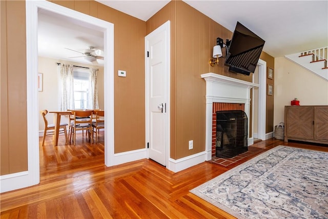 59 Davis Ave, Cranston, RI 02910 - living area with stairs, wood finished floors, a brick fireplace, a ceiling fan, and baseboards