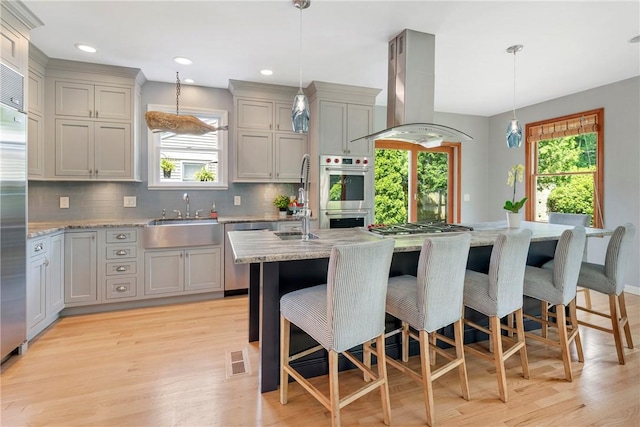 137 Congdon Ave, North Kingstown, RI 02852 - kitchen with island exhaust hood, appliances with stainless steel finishes, gray cabinetry, light wood-style floors, and recessed lighting