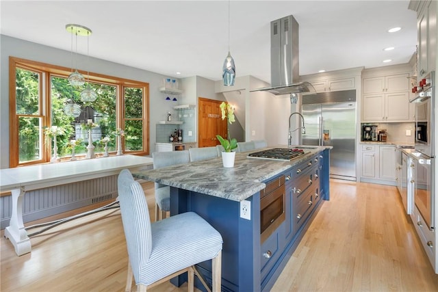 137 Congdon Ave, North Kingstown, RI 02852 - kitchen featuring built in appliances, island exhaust hood, light wood-style flooring, white cabinets, and tasteful backsplash