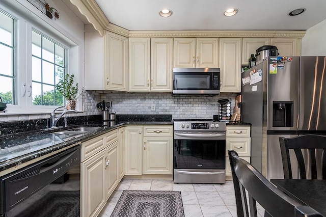 223 Corey Ln, Middletown, RI 02842 - kitchen featuring appliances with stainless steel finishes, cream cabinets, backsplash, dark stone counters, and light marble finish flooring