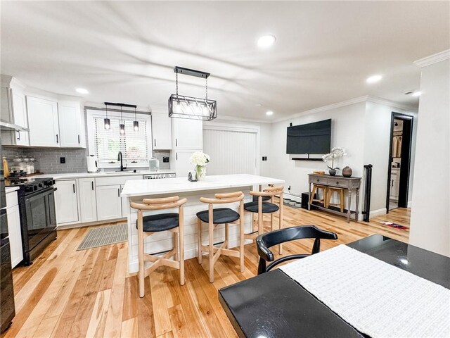 1 Sharp St, Coventry, RI 02816 - kitchen with black range with gas stovetop, crown molding, white cabinets, light wood-style floors, and a breakfast bar