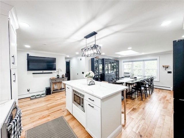 1 Sharp St, Coventry, RI 02816 - kitchen with stainless steel microwave, a skylight, freestanding refrigerator, white cabinetry, and crown molding