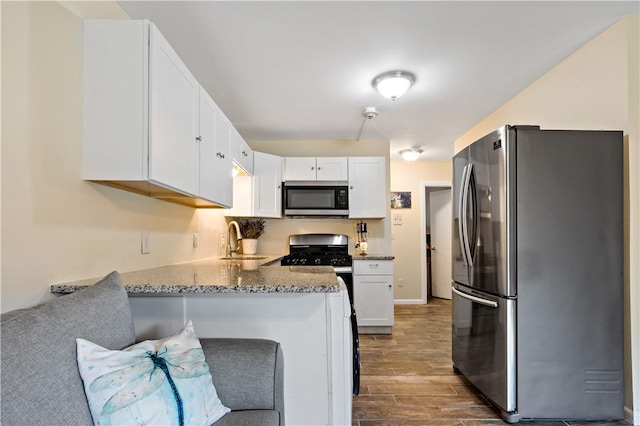 3940 Post Rd Unit 30, Warwick, RI 02886 - kitchen featuring appliances with stainless steel finishes, a sink, white cabinets, dark wood-type flooring, and a peninsula