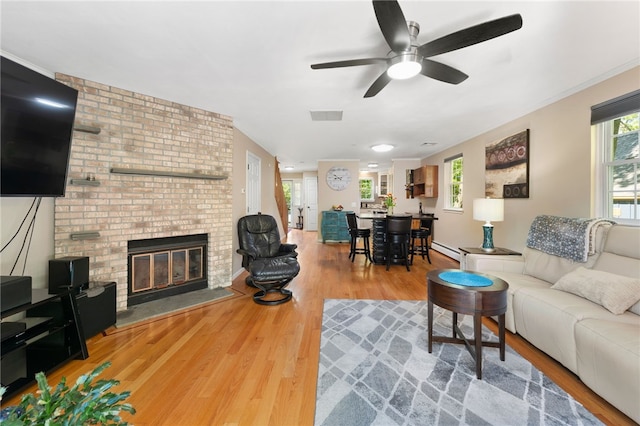 99 Post Rd Unit F1, Warwick, RI 02888 - living room with wood finished floors, ceiling fan, a brick fireplace, and a baseboard heating unit