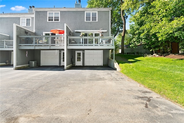 99 Post Rd Unit F1, Warwick, RI 02888 - rear view of house featuring central air condition unit, a deck, a lawn, a chimney, and an attached garage