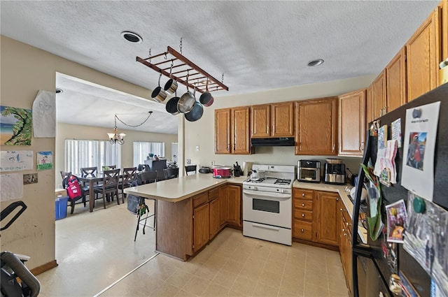 179 Armistice Blvd, Pawtucket, RI 02860 - kitchen featuring gas range gas stove, a peninsula, range hood, brown cabinets, and light countertops