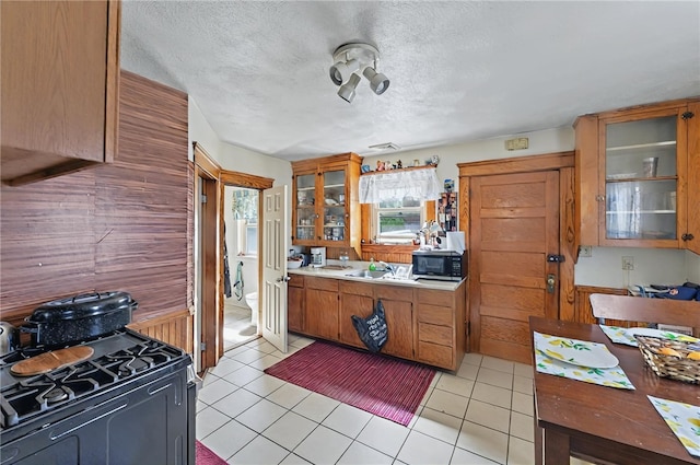 179 Armistice Blvd, Pawtucket, RI 02860 - kitchen with stainless steel microwave, black gas range, a textured ceiling, glass insert cabinets, and light countertops