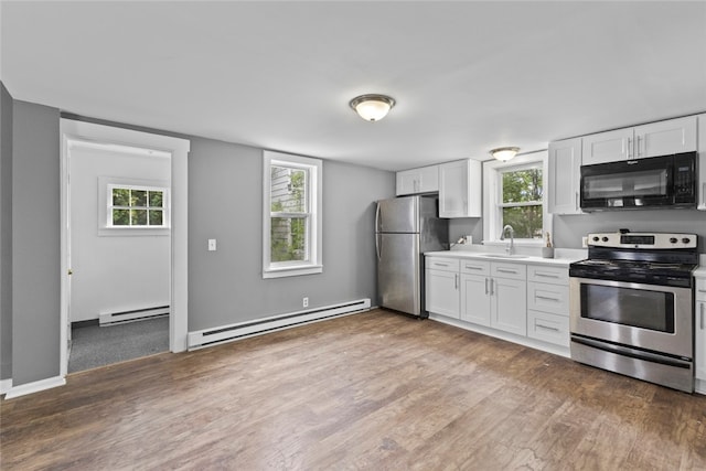 10 Sisson St, West Warwick, RI 02893 - kitchen featuring stainless steel appliances, baseboard heating, a sink, and wood finished floors