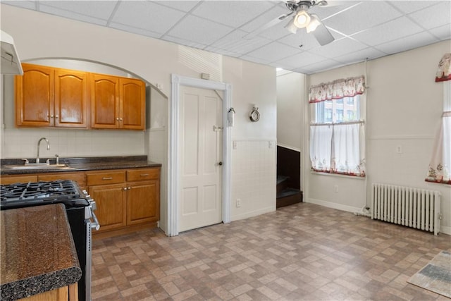 483 Dexter St, Providence, RI 02907 - kitchen with radiator, a sink, stainless steel gas range, a ceiling fan, and a drop ceiling