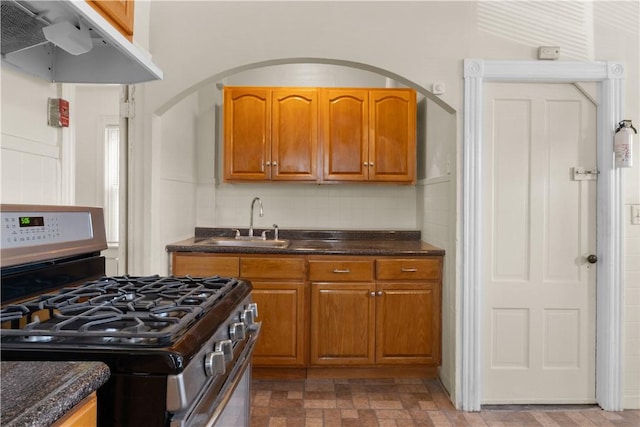 483 Dexter St, Providence, RI 02907 - kitchen featuring gas range, ventilation hood, a sink, brown cabinets, and arched walkways