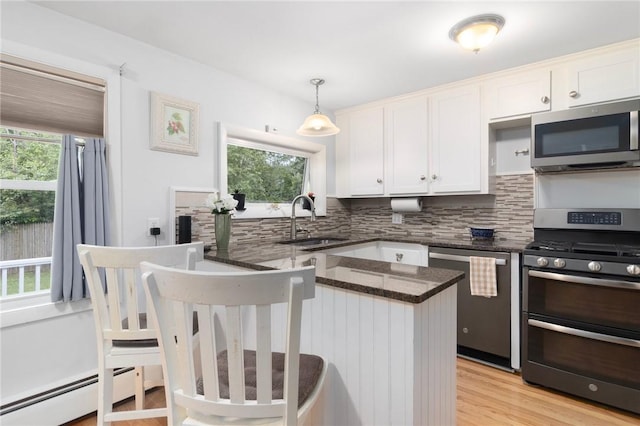 80 Flagg Ave, Warwick, RI 02886 - kitchen with stainless steel appliances, a sink, backsplash, a baseboard heating unit, and white cabinets