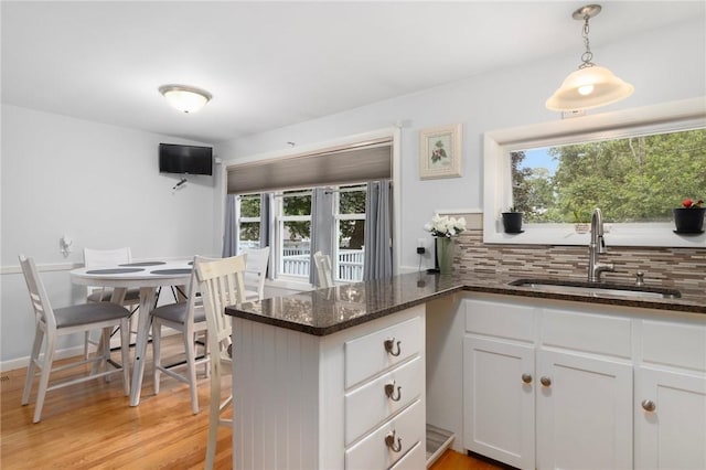 80 Flagg Ave, Warwick, RI 02886 - kitchen with a sink, white cabinetry, dark stone countertops, tasteful backsplash, and light wood finished floors