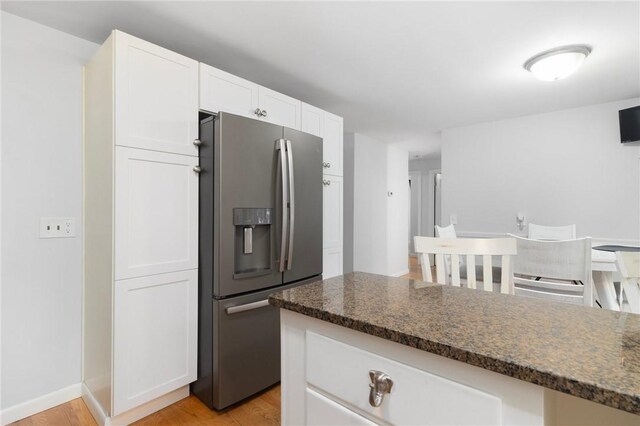80 Flagg Ave, Warwick, RI 02886 - kitchen with stainless steel fridge, light wood-style floors, white cabinets, and dark stone countertops