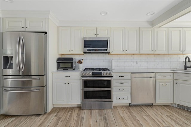 2 Carvin Ct, Warwick, RI 02886 - kitchen with appliances with stainless steel finishes, a sink, light countertops, light wood-type flooring, and decorative backsplash
