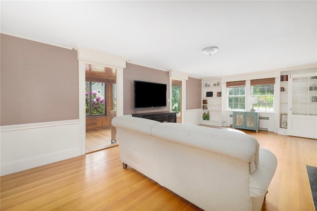 2 Carvin Ct, Warwick, RI 02886 - living room featuring radiator heating unit, light wood-style flooring, a wainscoted wall, built in shelves, and ornamental molding