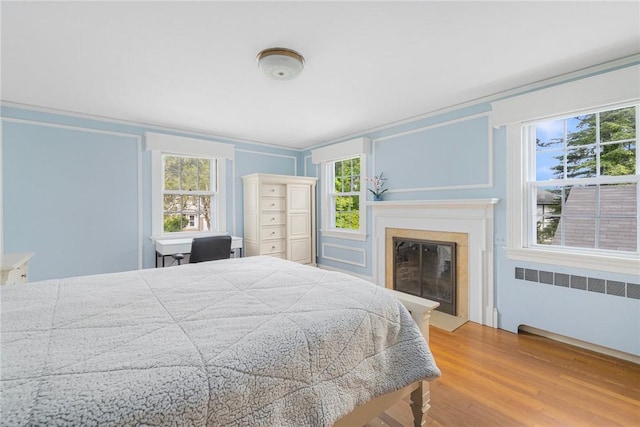 2 Carvin Ct, Warwick, RI 02886 - bedroom with radiator heating unit, a glass covered fireplace, wood finished floors, and crown molding