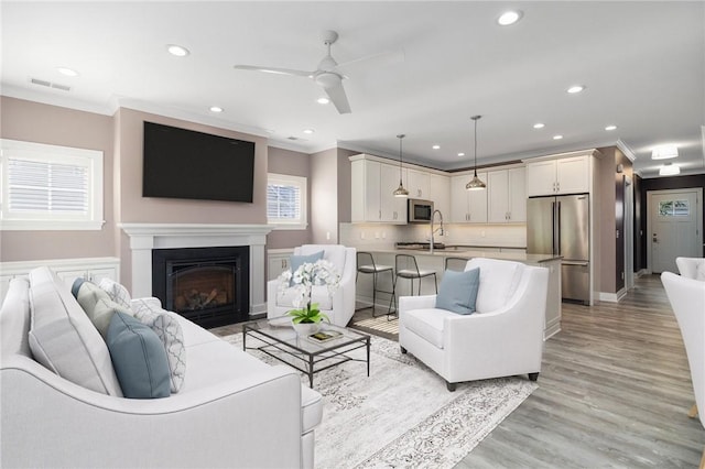 23 Middleberry Ln, East Greenwich, RI 02818 - living room with crown molding, recessed lighting, a ceiling fan, light wood finished floors, and a glass covered fireplace
