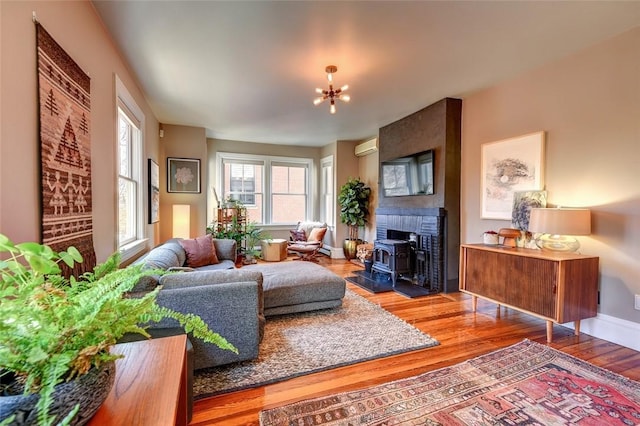 384 Benefit St Unit 2, Providence, RI 02903 - living area with wood finished floors, a wall mounted AC, a chandelier, baseboards, and a wood stove