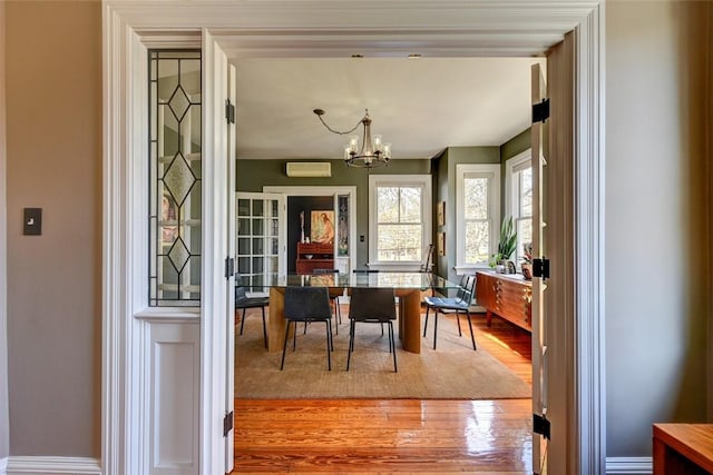 384 Benefit St Unit 2, Providence, RI 02903 - dining space featuring a chandelier, wood finished floors, an AC wall unit, and baseboards