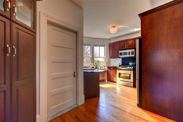 384 Benefit St Unit 2, Providence, RI 02903 - kitchen featuring stainless steel appliances, light wood-type flooring, tasteful backsplash, dark countertops, and glass insert cabinets