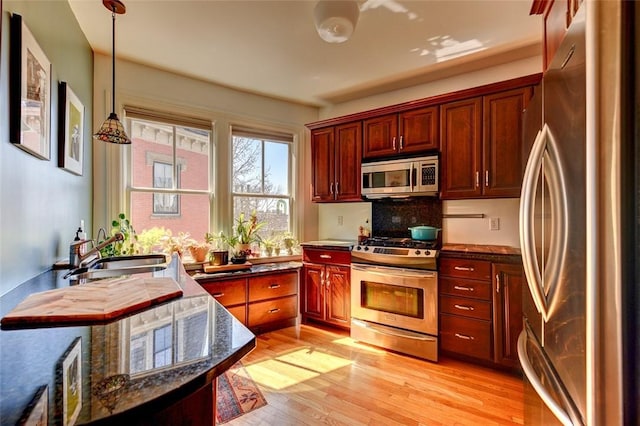 384 Benefit St Unit 2, Providence, RI 02903 - kitchen featuring stainless steel appliances, a sink, hanging light fixtures, light wood finished floors, and reddish brown cabinets