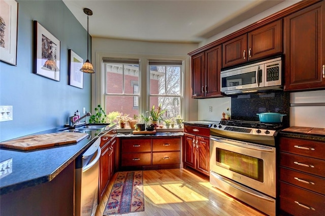 384 Benefit St Unit 2, Providence, RI 02903 - kitchen with appliances with stainless steel finishes, dark countertops, light wood finished floors, decorative light fixtures, and backsplash