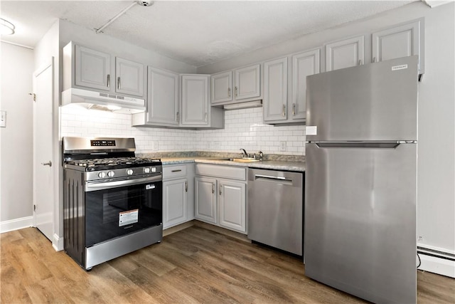 3940 Post Rd Unit 38, Warwick, RI 02886 - kitchen with stainless steel appliances, under cabinet range hood, a baseboard heating unit, a sink, and light wood-style flooring
