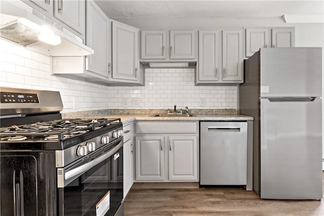 3940 Post Rd Unit 38, Warwick, RI 02886 - kitchen with stainless steel appliances, under cabinet range hood, a sink, decorative backsplash, and light countertops